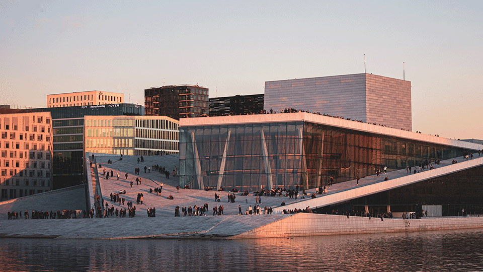 Kuva Oslon oopperatalosta auringonlaskun aikaan. Sen kulmikas ulkopinta on valkoista graniittia.